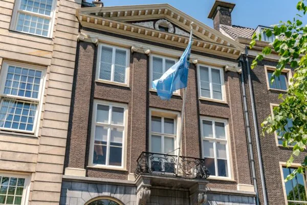 Voorgevel van een klassiek herenhuis aan de Lange Vijverberg met een blauwe vlag en smeedijzeren balkon.